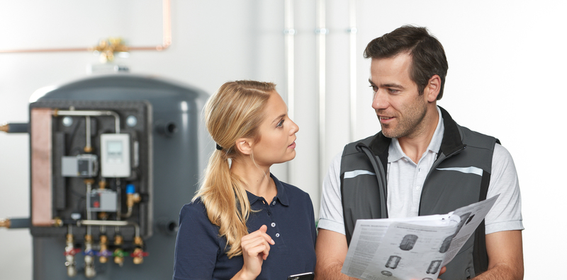 DITECH Beratungsgespräch DITECH Handwerker erläutert einer Endkundin im Heizungskeller die Kennzeichnung des Energieverbrauchs über das Energielabel.
